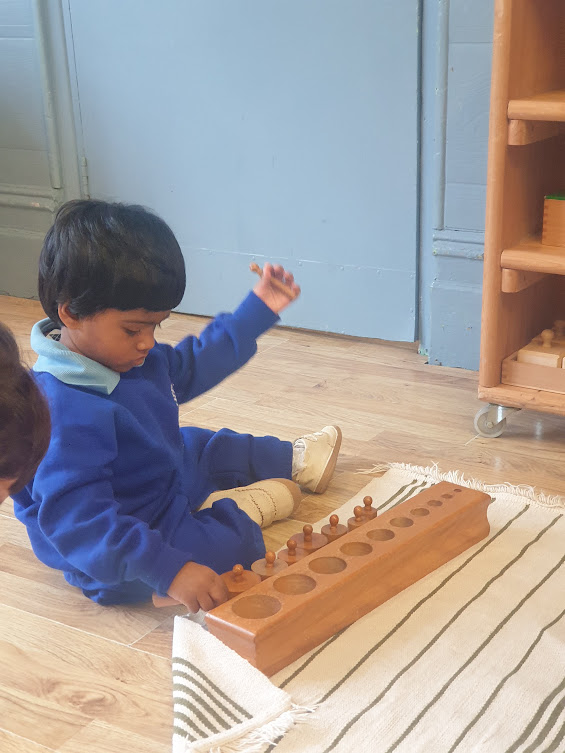 A child exploring a sensory activity with a teacher