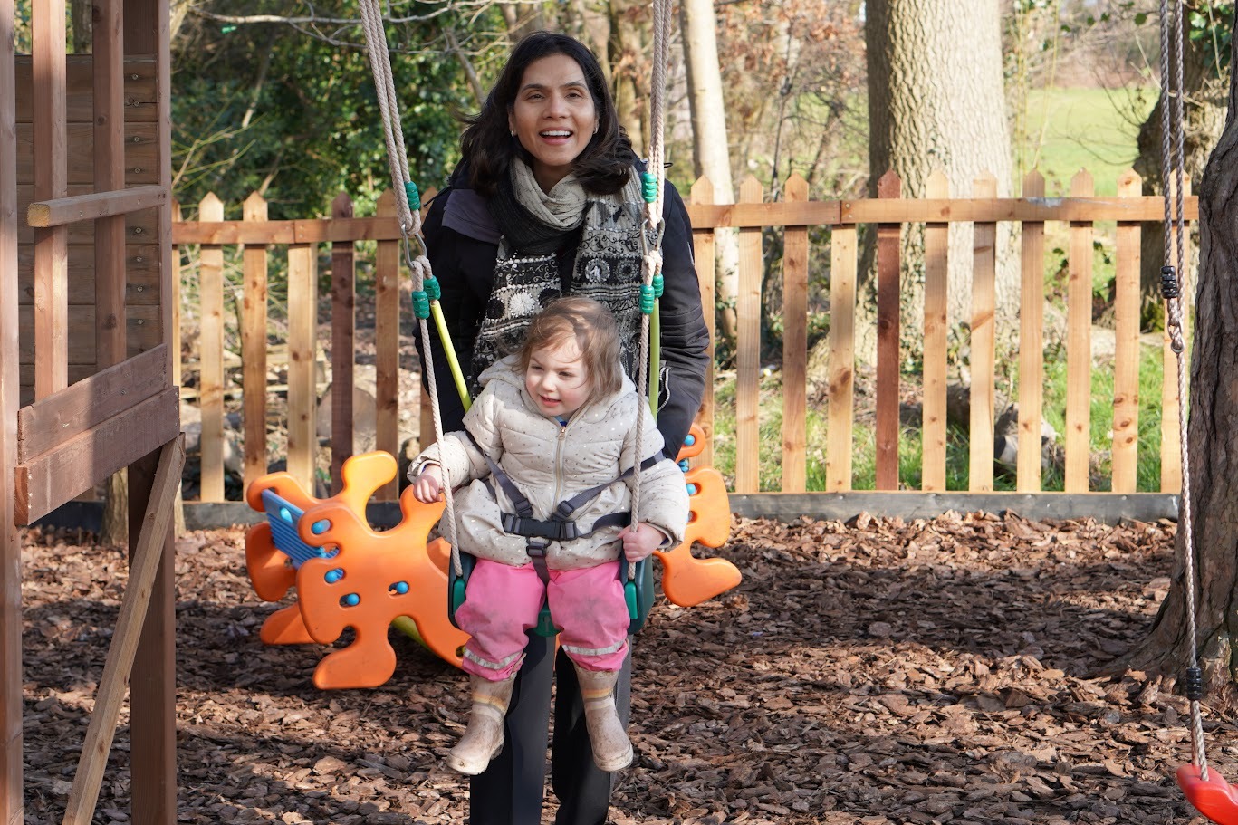 A member of staff holding a child outdoors at Little Elms